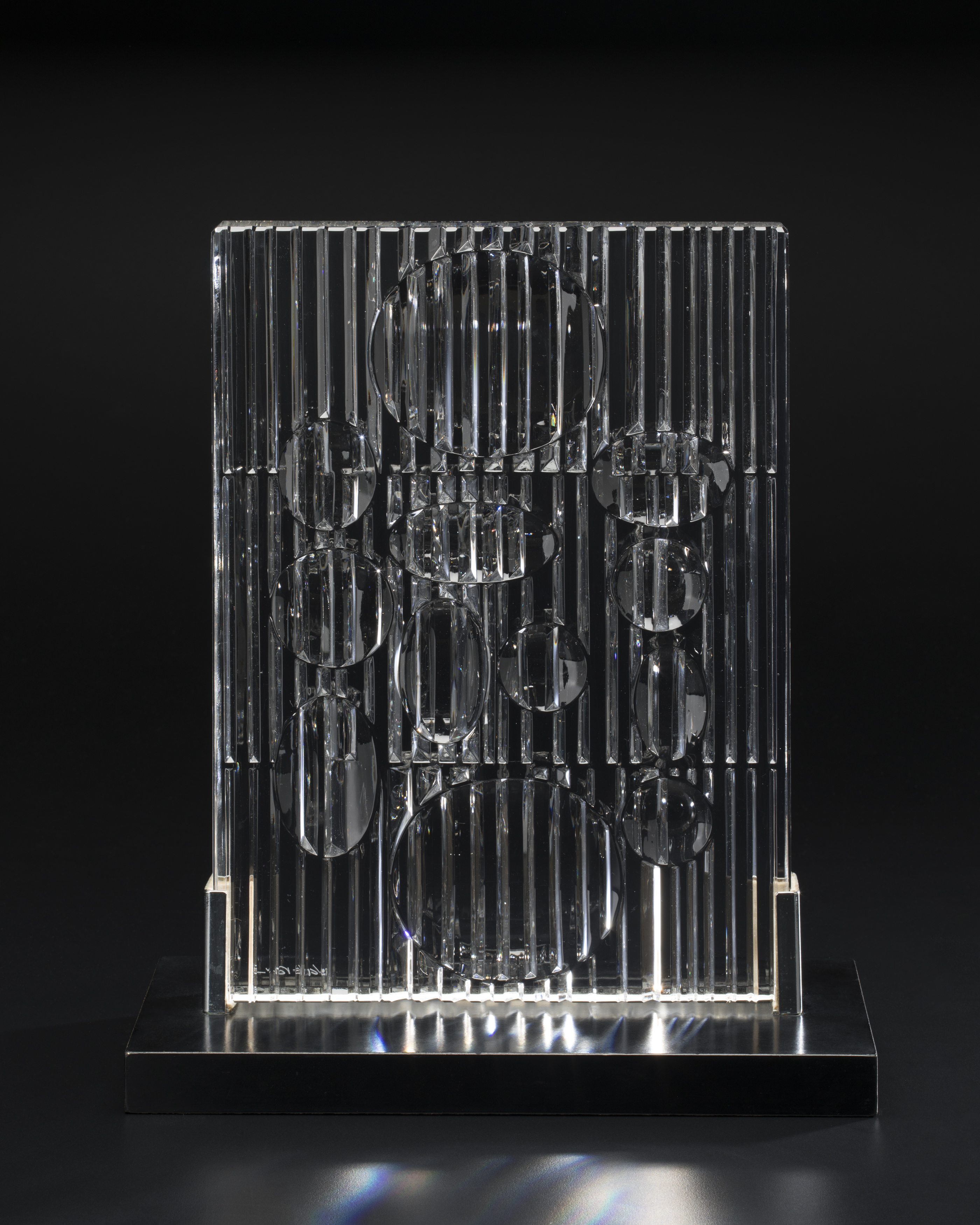 Standing rectangular panel in clear and brilliantly cut crystal, vertically reeded with round depressions which act as lenses to magnify the reeding and produce a rainbow-coloured effect on the crystal. 